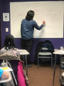 A Grade Ahead of Des Moines Enrichment Academy Classroom Teacher Student White Board Lesson