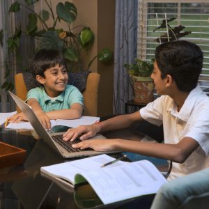 Happy siblings at kitchen table with online tutoring classes